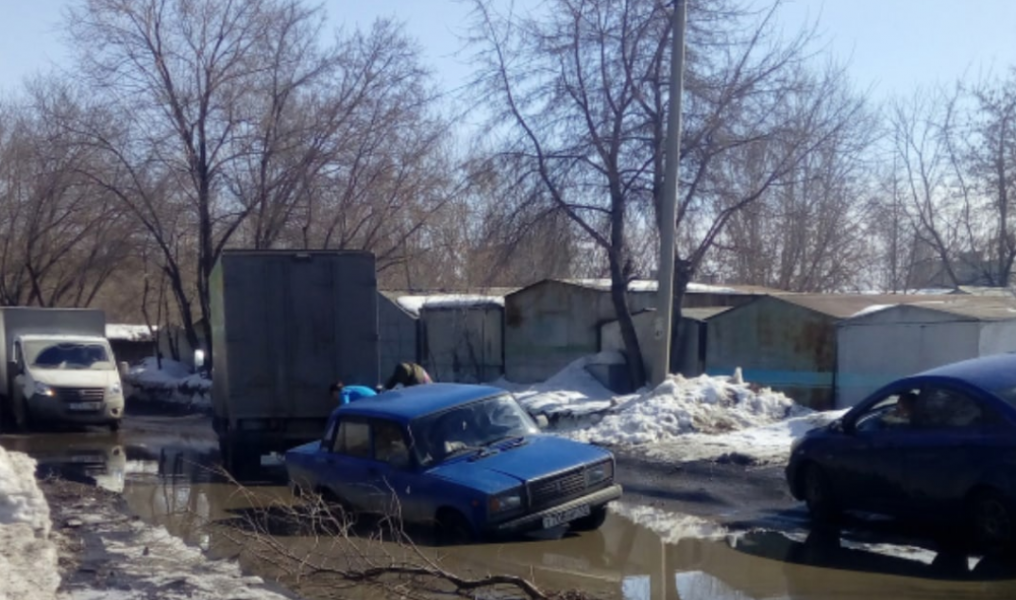 На омской улице машина утонула в луже и смогла выбраться только с помощью грузовика